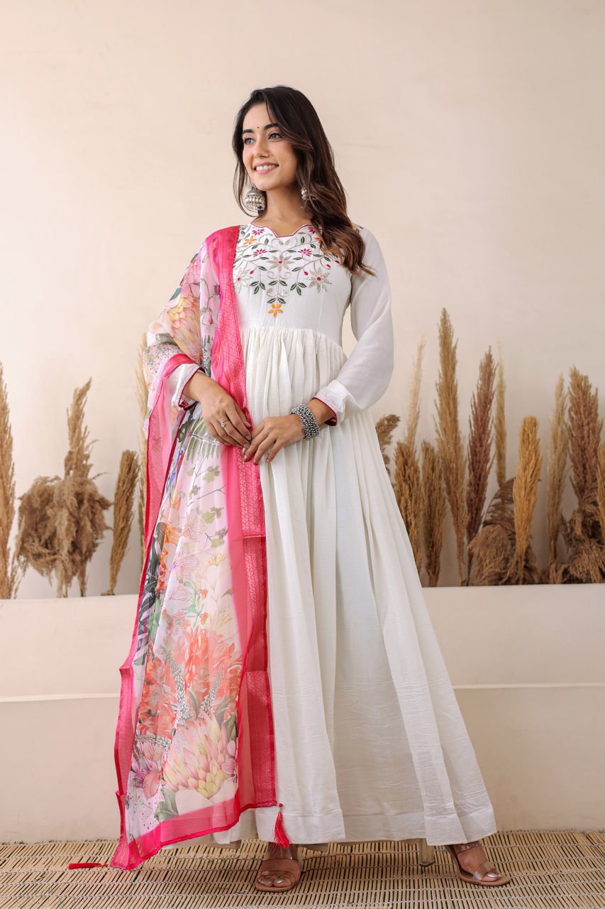 Elegant white Anarkali with floral embroidery, paired with a vibrant floral dupatta. Graceful, festive, and perfect for any celebration.
