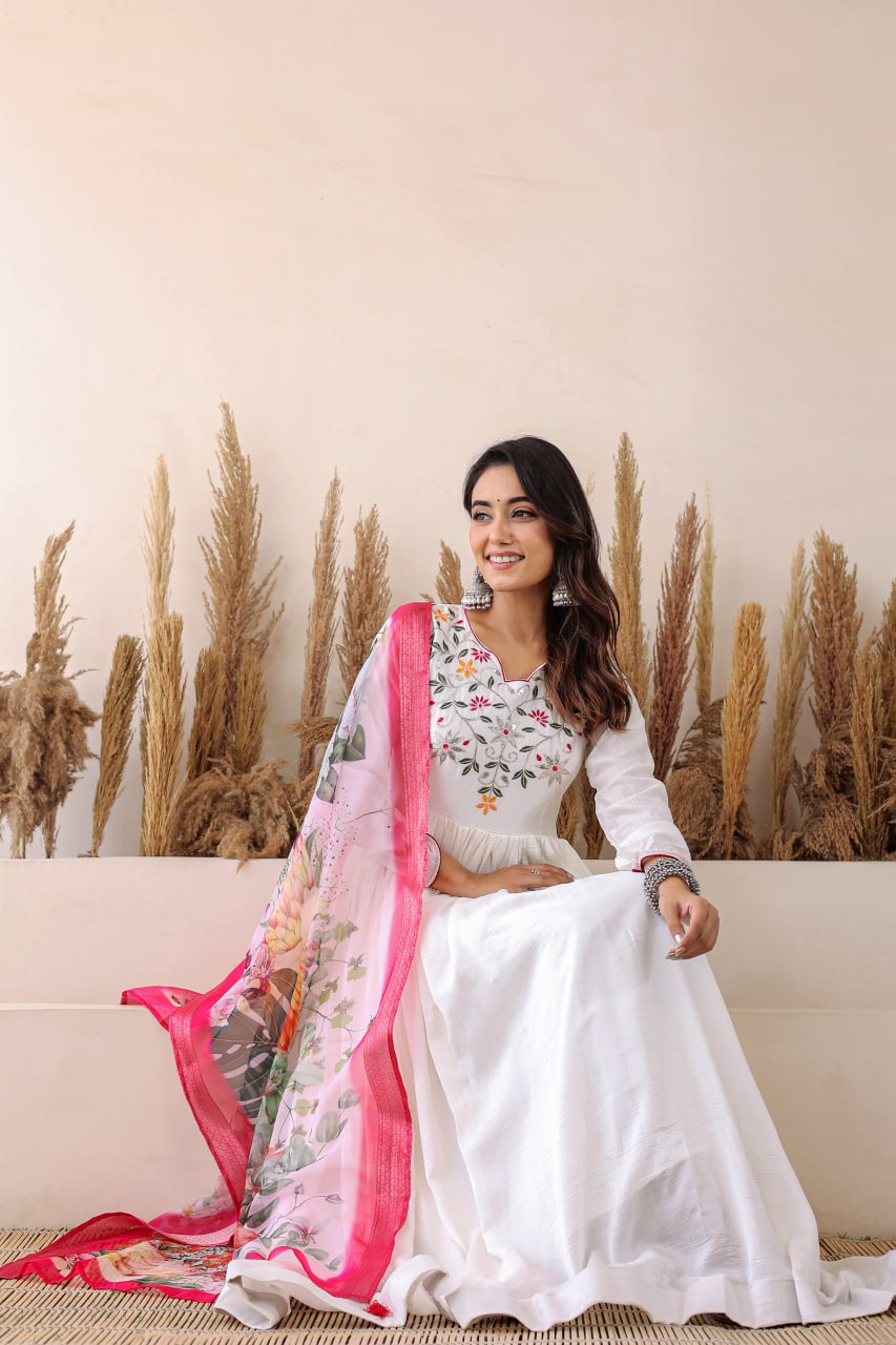 Elegant white Anarkali with floral embroidery, paired with a vibrant floral dupatta. Graceful, festive, and perfect for any celebration.